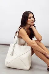 Bolso tipo shopper color rojo, confeccionado en 100% cuero vacuno, con diseño geométrico de paneles y detalle de fleco decorativo colgante.
