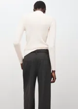 Jersey de punto canalé color blanco roto, de corte ajustado, con cuello alto y manga larga.