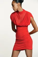 Vestido corto rojo confeccionado en tejido mesh. Cuello alto y manga sisa con frunces. Bajo combinado a tono con drapeado a los lados. Cierre lateral con cremallera oculta en costura.