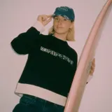Buzo Rip Curl de punto color negro con diseño de bloques de color, presenta paneles en color crudo en los puños, cuello y el borde inferior. Incluye la inscripción "Rip Curl" bordada en el pecho con tipografía estilo gótico.