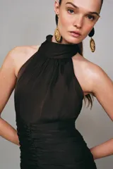 Vestido corto de cuello halter con espalda descubierta, diseño con frunces en el cuerpo y bajo con lentejuelas brillantes. Cuenta con forro interior y cierre trasero con cremallera oculta.
