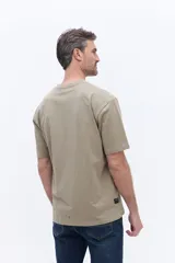 Remera de manga corta color beige, con cuello redondo y estampa gráfica central con motivos botánicos y texto.