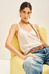 Top negro de viscosa con breteles finos y escote en V con puntilla. Presenta apliques de tachas termo adhesivas en el frente.