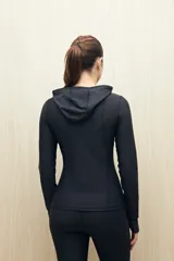 Campera deportiva negra de calce entallado, con cierre frontal completo, capucha integrada y mangas largas con puños envolventes. Presenta costuras estratégicas que estilizan la silueta y bolsillos laterales funcionales.
