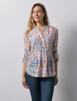Blusa de gasa estampada con flores en tonos rosa, amarillo y azul. Tiene cuello a la base, escote en V y botones. La delantera tiene detalle plisado y las mangas son 3/4 regulables con presilla y botón.