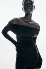 Top negro ajustado de punto suave, con hombros descubiertos y escote con doblez amplio. Modelo de manga larga con bajo de corte recto.