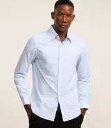 Camisa de manga larga color celeste, con cuello inglés y abotonado delantero. Confeccionada en tricolina con fibra de bambú, presenta un diseño maquinetado con estampado de rayas.