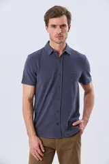 Camisa de piqué lisa color celeste, de manga corta, con cuello camisero y cierre frontal de botones oscuros.
