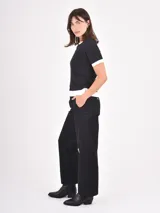 Pantalon de corte recto y tiro medio, confeccionado en tela de algodón color negro, con cierre frontal y bolsillos laterales.