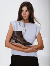 Botinetas de caña baja confeccionadas en una combinación de cuero napa y gamuza en tono bordó. Presentan un diseño de paneles con una banda central horizontal, puntera cuadrada y taco geométrico de color negro.