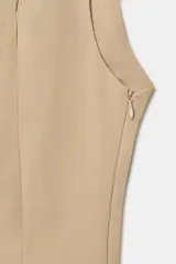 Top entallado de cuello subido y manga sisa, con detalle de botones a presión metálicos en el delantero. Cuenta con forro interior y cierre lateral con cremallera oculta.