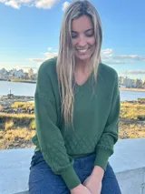 Sweater de punto verde oscuro, confeccionado en hilado de viscosa y lycra, con escote en V y diseño de rombos texturizados en la parte inferior y las mangas.