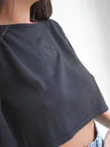 Top corto azul marino de punto, con mangas cortas amplias, cuello redondo y detalle de escudo bordado en la parte delantera.