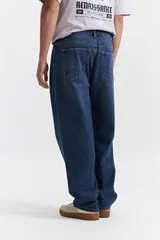 Jean de corte baggy con tiro medio, diseño amplio y holgado en piernas y cadera, con pasacintos y cierre frontal.