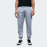 Pantalón de jogging gris con cintura elástica ajustable mediante cordón, puños en los tobillos y logo de la marca bordado en la pierna izquierda.