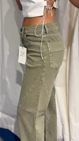 Pantalón de jean verde con corte recto y diseño de costuras diagonales en la parte delantera.