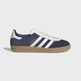 Championes Adidas Gazelle Indoor, color azul marino con tres franjas y detalles en blanco. Presentan un exterior de gamuza y cuero sintético, forro blanco y suela de goma traslúcida color caramelo.
