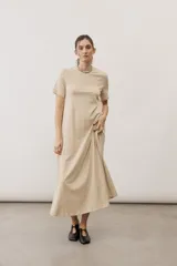 Vestido midi negro con diseño de manga corta, cuello redondo y bolsillos laterales, corte amplio y fluido.
