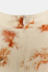 Vestido corto sin mangas de cuello redondo, con estampado tie-dye en tonos beige, naranja y verde oscuro. Presenta un lazo para atar en la cintura y cierre trasero con cremallera oculta.
