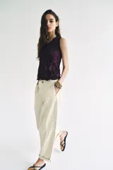 Pantalón de tiro bajo estilo chino, color blanco, con bolsillos delanteros, bolsillos de plastrón en la espalda y bajo acabado con vuelta. Cierre frontal con cremallera y botón.