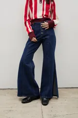 Pantalón de denim tiro alto con corte oxford y tajos laterales en el ruedo. Presenta cierre frontal con botones a la vista y costuras verticales decorativas.