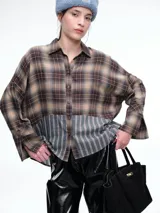 Camisa de corte relajado con diseño combinado. La parte superior presenta un estampado a cuadros en tonos marrones y negros, mientras que la parte inferior destaca por un panel de rayas verticales en color bordó. Cuenta con cierre frontal de botones y mangas largas.