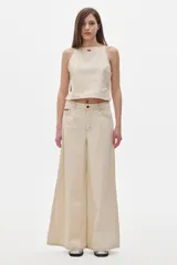 Pantalón jean color crema, de tiro alto y corte wide leg.