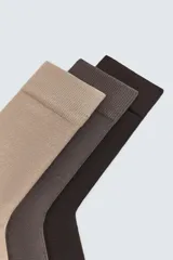 Pack de tres pares de calcetines de hombre en tonos neutros: beige, marrón oscuro y negro. Tejidos en hilatura con mezcla de algodón y acabados en rib elástico.
