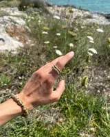 Pulsera artesanal compuesta por una serie de cuentas metálicas irregulares ensartadas en un hilo de algodón natural. Diseño rústico y minimalista.