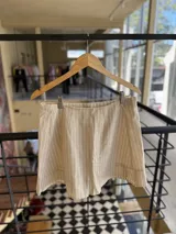 Minifalda beige con rayas verticales blancas, corte a la cintura y volados en diagonal en el frente.