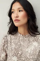 Blusa color beige con estampado abstracto en blanco, corte relajado, mangas 3/4 fruncidas y cuello con volados.