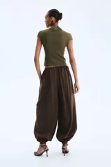 Top de punto suave verde militar, de corte ceñido, cuello alto y mangas cortas con aberturas laterales en las sisas.
