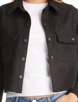 Chaqueta de estilo camisero confeccionada en tejido tipo suede, con cuello clásico, cierre frontal mediante botones a presión y bolsillos aplicados en el pecho. Presenta mangas largas con puños ajustables.