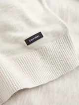 Sweater de punto color beige claro, con cuello redondo y logo de la marca en la parte inferior.