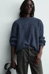 Jersey de punto con diseño de trenzas, cuello redondo y manga larga. Presenta un ajuste oversized y acabados en rib en puños y ruedo.