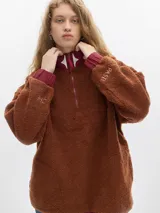 Buzo negro de fleece con cuello alto verde y cierre parcial con cremallera verde. Tiene puños con elástico azul y un bordado de un diamante blanco en el pecho.