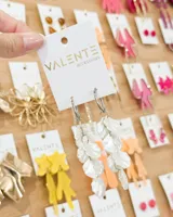 Aros colgantes compuestos por una argolla de acero y una serie de pétalos de resina en color blanco nacarado dispuestos en cascada.