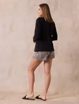 Pijama de dos piezas compuesto por una remera negra de manga larga con escote redondo y bolsillo en el pecho, y un short con estampado animal print.