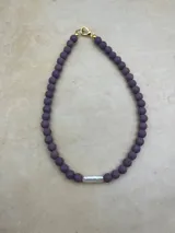 Collar artesanal compuesto por cuentas de piedra volcánica en diversos tonos y tamaños, con una perla natural de río como dije central y cierre metálico dorado.