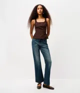 Pantalón de jean corte bootcut con tiro bajo, confeccionado en denim de algodón con lavado dirty que aporta un efecto envejecido. Presenta cierre frontal con botón y cremallera, presillas en la cintura y detalle de tachas metálicas en los bolsillos frontales.