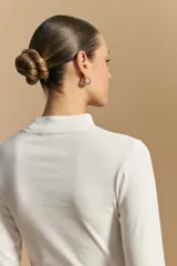 Polera de manga larga color marrón claro, con cuello alto y costura vertical decorativa en el frente.