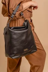 Cartera bandolera de gran tamaño en símil cuero color marrón con efecto desgastado. Cuenta con asa corta fija, correa larga regulable y placa metálica con logo en la parte frontal.
