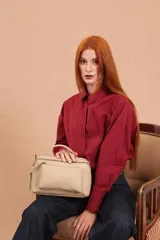 Bandolera de diseño rectangular con asa superior y correa larga ajustable. Presenta dos bolsillos frontales, uno de ellos con cierre, y logo grabado en la parte inferior.