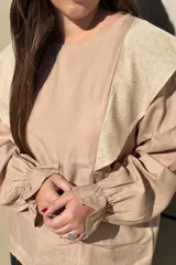 Blusa de algodón color bordó, con diseño de volados en los hombros, mangas largas con puños elásticos y corte holgado.