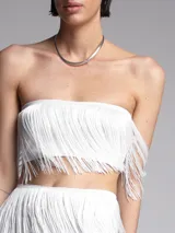 Conjunto de top bandeau y falda midi, ambos blancos con flecos.