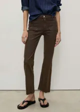 Pantalón tipo jeans de corte flare y diseño crop, color marrón. Presenta tiro medio, cierre frontal con cremallera y botón, trabillas para cinturón y dos bolsillos de parche en la parte delantera. El ruedo tiene un acabado deshilachado.