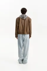 Chaqueta estilo bomber de cuero sintético color marrón, con cuello camisero, cierre frontal y bolsillos delanteros con solapa.