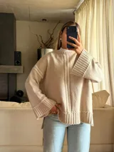 Sweater de punto oversize color beige, con cuello redondo, mangas largas acampanadas y detalles de bordado artesanal en relieve a lo largo del frente y las mangas.