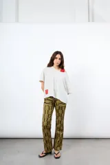 Pantalón de pana tiro alto color óxido, de corte flare y pierna ancha. Cuenta con botonadura frontal metálica y bolsillos plaqué delanteros.