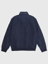 Campera bomber Tommy Hilfiger azul marino con cuello alto, cierre frontal con cremallera, dos bolsillos laterales con cremallera, puños y bajo elásticos. Tiene el logo de Tommy Hilfiger bordado en el pecho y un parche con el logo en la manga izquierda. El interior del cuello tiene detalles en rojo, blanco y azul.